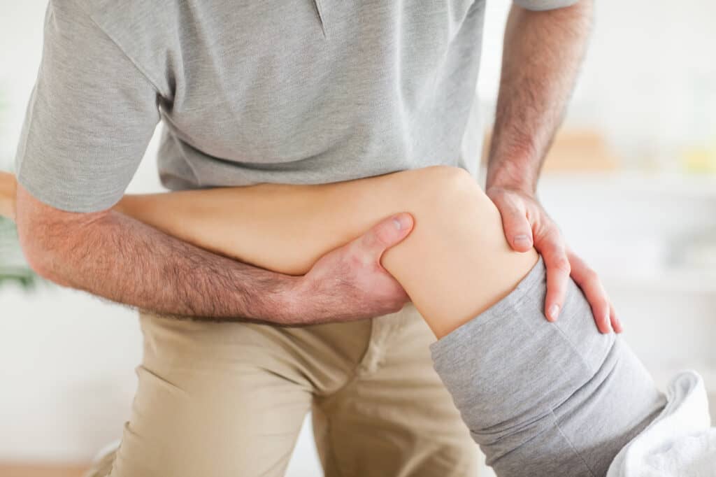 Chiropractor massaging a woman's knee in a room