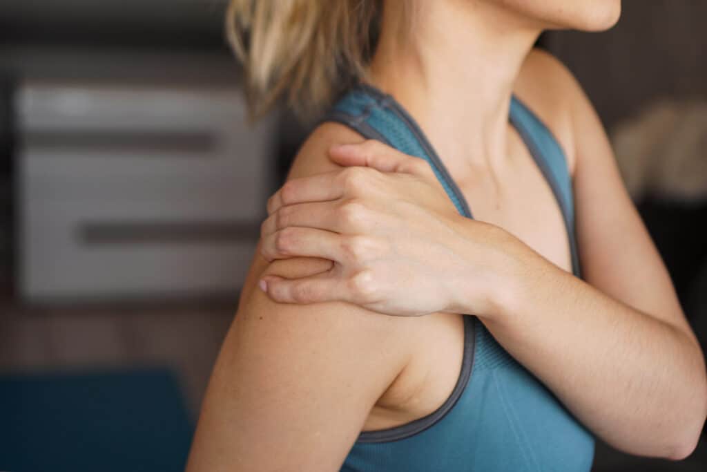 Closeup on fitness woman having pain in shoulder. Pain after home workout