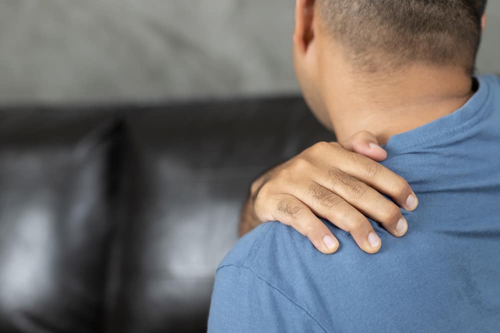 Man has neck pain, shoulder pain sitting on sofa at home